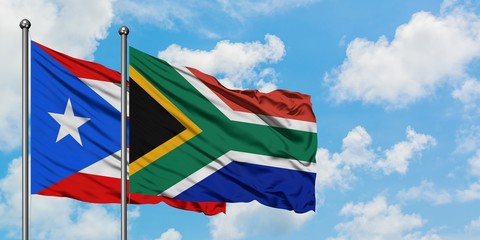 Puerto Rico and South Africa flag waving in the wind against white cloudy blue sky together. Diplomacy concept, international relations.