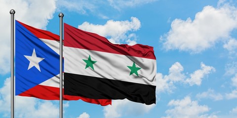 Puerto Rico and Syria flag waving in the wind against white cloudy blue sky together. Diplomacy...