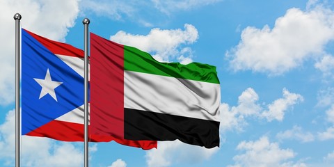 Puerto Rico and United Arab Emirates flag waving in the wind against white cloudy blue sky together. Diplomacy concept, international relations.