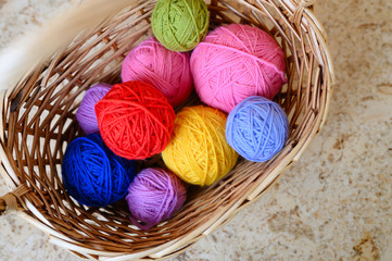 Fototapeta na wymiar wicker basket with multicolored bright balls of wool yarn for knitting