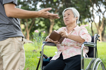 Obraz premium Asian male having a cash problem,demanding money,stressed man asking for money from senior woman,mother pulls out pocket money from wallet to give her son,economic downturn,bankrupt concept