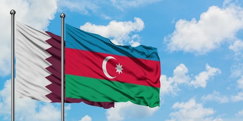 Qatar and Azerbaijan flag waving in the wind against white cloudy blue sky together. Diplomacy concept, international relations.