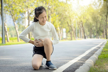 Sick asian child girl holding her hands on belly having stomach painful in the right side attack of appendicitis,female teenage suffer from stomachache feel acute pain,appendicitis symptoms at park