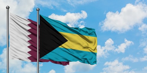 Qatar and Bahamas flag waving in the wind against white cloudy blue sky together. Diplomacy concept, international relations.