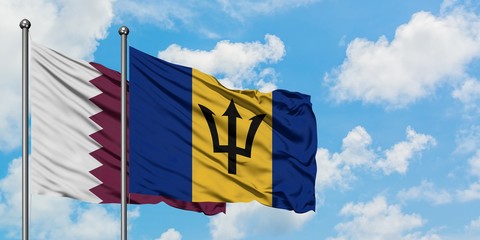 Qatar and Barbados flag waving in the wind against white cloudy blue sky together. Diplomacy concept, international relations.