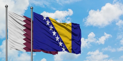 Qatar and Bosnia Herzegovina flag waving in the wind against white cloudy blue sky together....