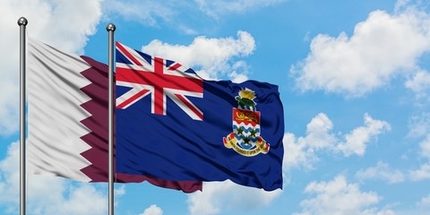 Qatar and Cayman Islands flag waving in the wind against white cloudy blue sky together. Diplomacy concept, international relations.