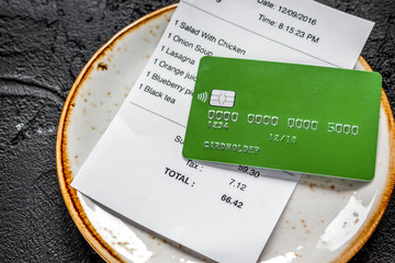 paying check for lunch in cafe with credit card on dark table background