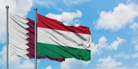 Qatar and Hungary flag waving in the wind against white cloudy blue sky together. Diplomacy concept, international relations.
