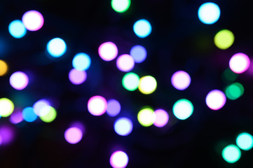 blurred night multicolored glowing lights on black background. new year and christmas concept