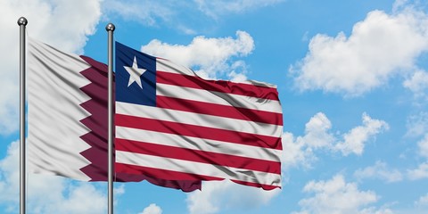 Qatar and Liberia flag waving in the wind against white cloudy blue sky together. Diplomacy concept, international relations.