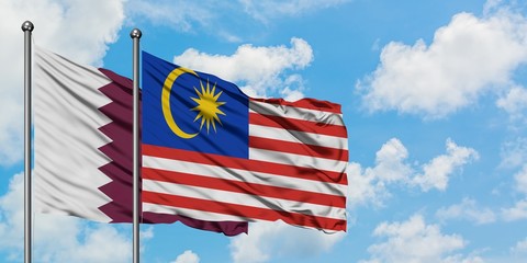 Qatar and Malaysia flag waving in the wind against white cloudy blue sky together. Diplomacy concept, international relations.
