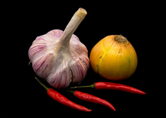 Onion, garlic and pods of hot pepper on a black background.