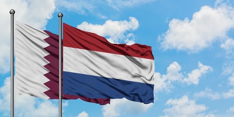 Qatar and Netherlands flag waving in the wind against white cloudy blue sky together. Diplomacy concept, international relations.