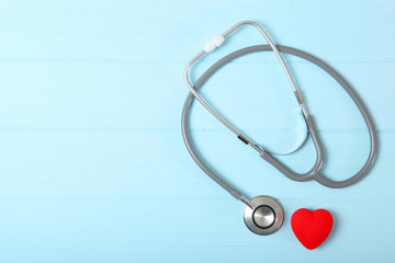 Stethoscope and heart on wooden color background. Health, medicine