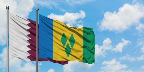 Qatar and Saint Vincent And The Grenadines flag waving in the wind against white cloudy blue sky...
