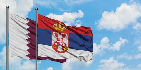 Qatar and Serbia flag waving in the wind against white cloudy blue sky together. Diplomacy concept, international relations.
