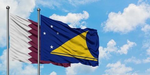 Qatar and Tokelau flag waving in the wind against white cloudy blue sky together. Diplomacy concept, international relations.