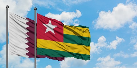 Qatar and Togo flag waving in the wind against white cloudy blue sky together. Diplomacy concept, international relations.