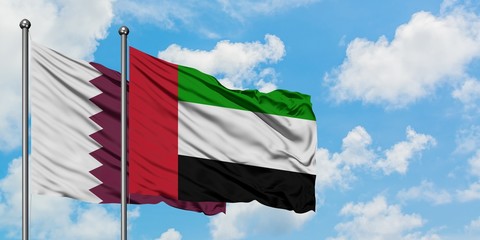Qatar and United Arab Emirates flag waving in the wind against white cloudy blue sky together. Diplomacy concept, international relations.