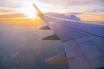 Fotobehang Beautiful sunset, sky on the top view, airplane flying view from inside window and cloud, sun down background aircraft of Traveling. © BBbirdZ