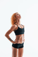 Fototapeta premium Redhead female bodybuilder is in the studio on white background