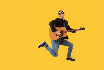 Jumping man with guitar on color background