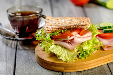 Sandwich with ham, cucumber, tomato and lettuce.