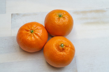 Group of three mandarines on wooden background