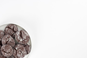 Chocolate crinkle cookies in round plate, white background. Christmas, recipe concept. Top view, flat lay, copy space