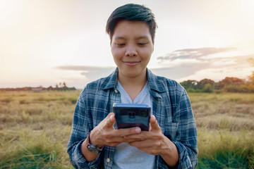 A lesbian or involving homosexual woman in a plaid shirt using smartphone outdoor - obrazy, fototapety, plakaty