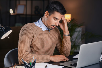 Tired businessman trying to meet deadline in office late in evening