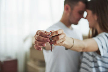 Image focus technique. House keys. Cheerful young couple in their new apartment. Conception of moving