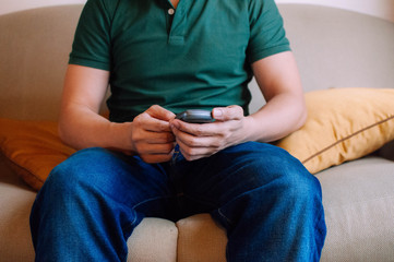 A young male adult is using a device to measure blood sugar while sitting on a couch