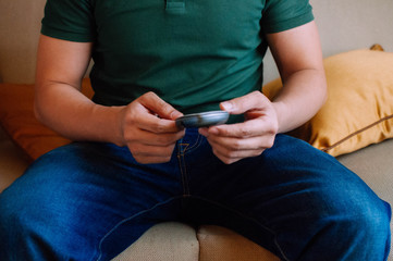 A young male adult is using a device to measure blood sugar while sitting on a couch