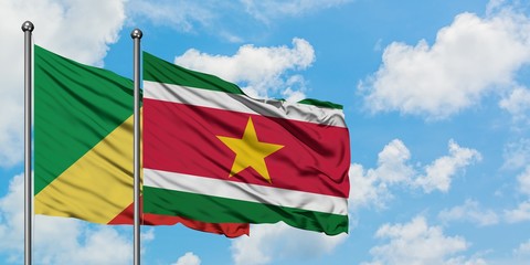 Republic Of The Congo and Suriname flag waving in the wind against white cloudy blue sky together. Diplomacy concept, international relations.