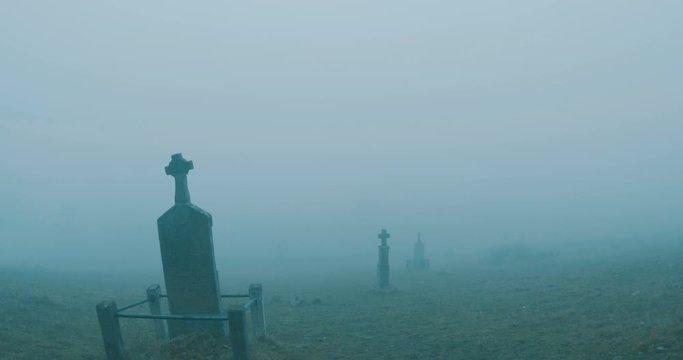 Walking along crosses on misty graveyard.