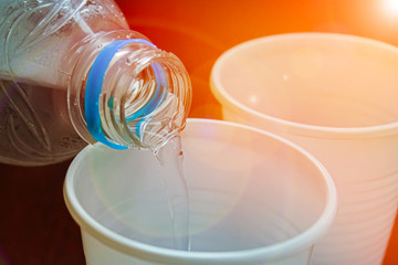 water is poured from a bottle into a plastic Cup