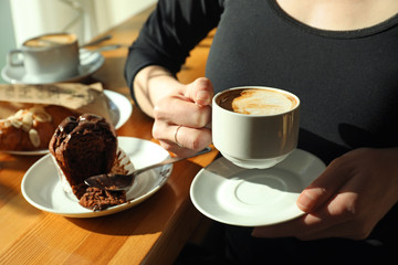 Woman with cup of fresh aromatic coffee at table in cafe