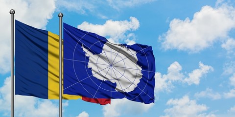 Romania and Antarctica flag waving in the wind against white cloudy blue sky together. Diplomacy...