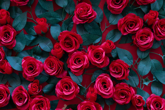 Artificial roses glued to the wall. Beautiful background of their bright red flowers - Powered by Adobe