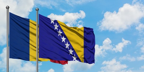 Romania and Bosnia Herzegovina flag waving in the wind against white cloudy blue sky together. Diplomacy concept, international relations.