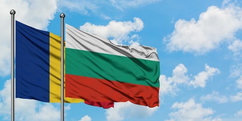 Romania and Bulgaria flag waving in the wind against white cloudy blue sky together. Diplomacy...