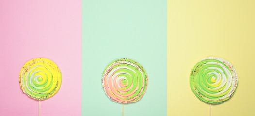 Colorful meringue on stick on colorful pastel background. Festive and party concept. Minimal style.