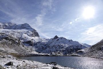 Fototapeta na wymiar a beautiful mountain lake in the snow capped alps in autumn on a sunny 