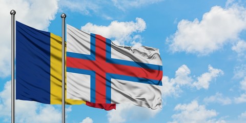 Romania and Faroe Islands flag waving in the wind against white cloudy blue sky together. Diplomacy concept, international relations.