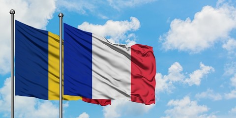 Romania and France flag waving in the wind against white cloudy blue sky together. Diplomacy...