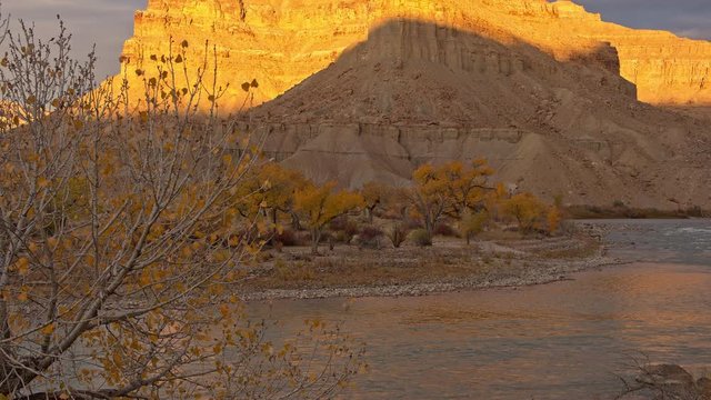 Tilt up of desert landscape as the sun shines on cliffs in Utah next to the Green River.