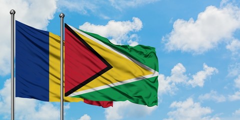 Romania and Guyana flag waving in the wind against white cloudy blue sky together. Diplomacy concept, international relations.