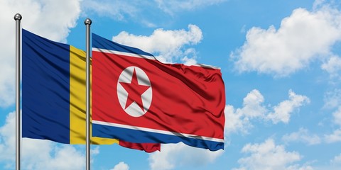 Romania and North Korea flag waving in the wind against white cloudy blue sky together. Diplomacy concept, international relations.